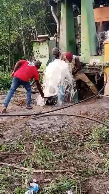 De l'eau jaillit du sol, entouré par les foreurs.
